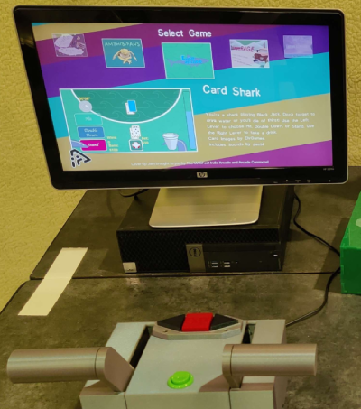 A computer monitor with Card Shark on screen, behind a large box with two levers and a button.