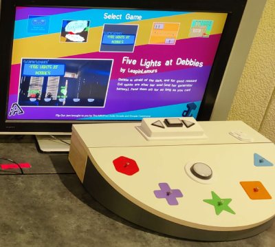 A computer monitor with Five Light's at Debbie's on screen, behind a box with five switches and a button.